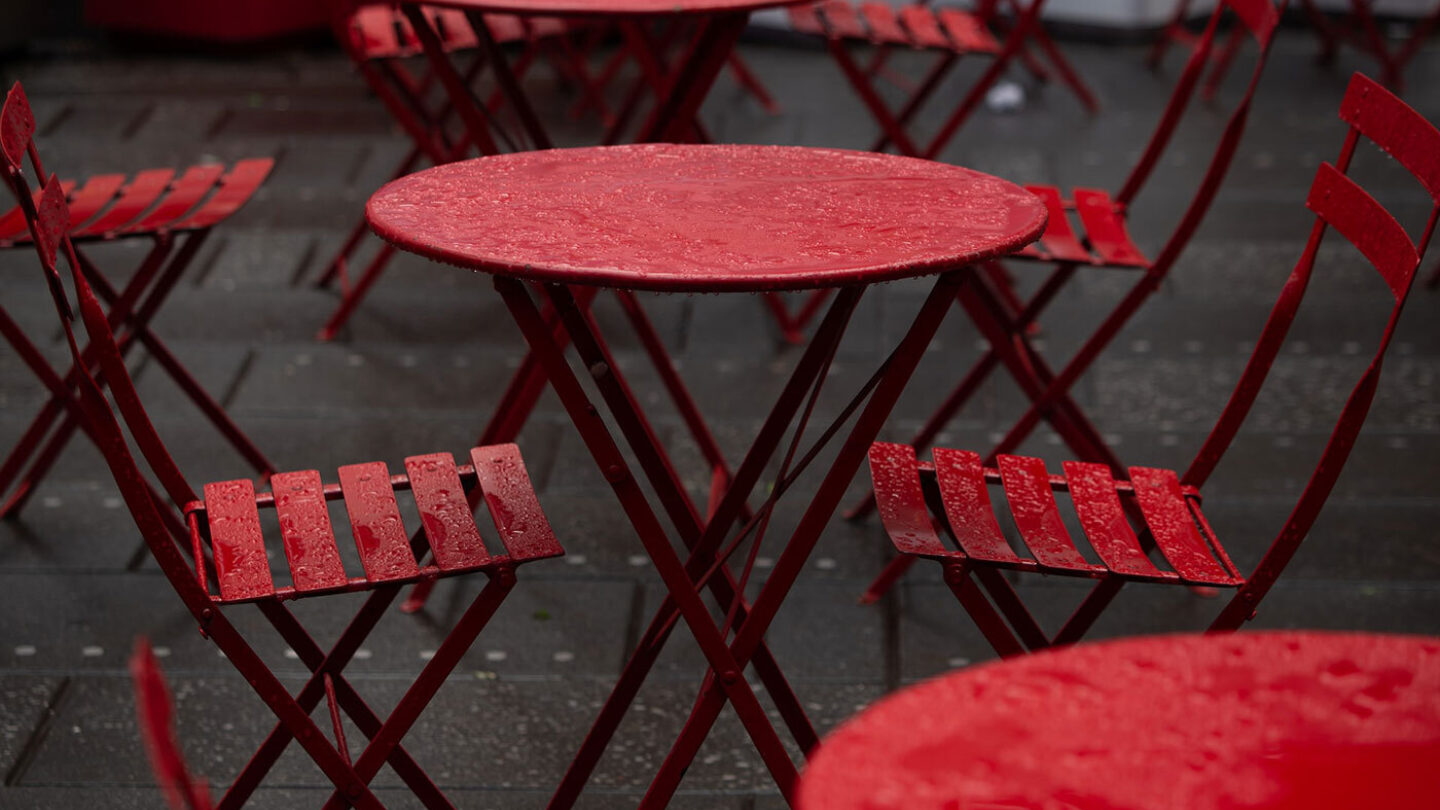 Red chair and tables outside, covered with raindrops